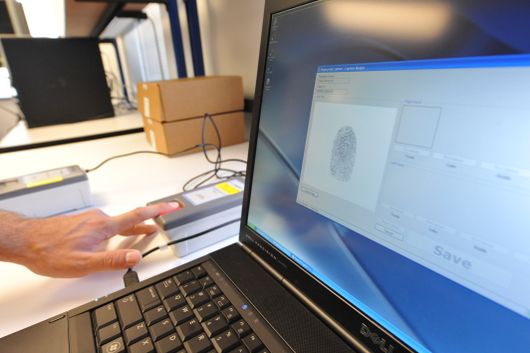 An image of a person scanning their fingerprint into the computer.