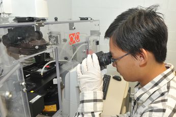 A student in computer engineering studies a microchip under a microscope.